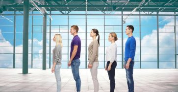 People standing in a single-file line inside a bright modern hall, illustrating the old queue system at UAE visa centers