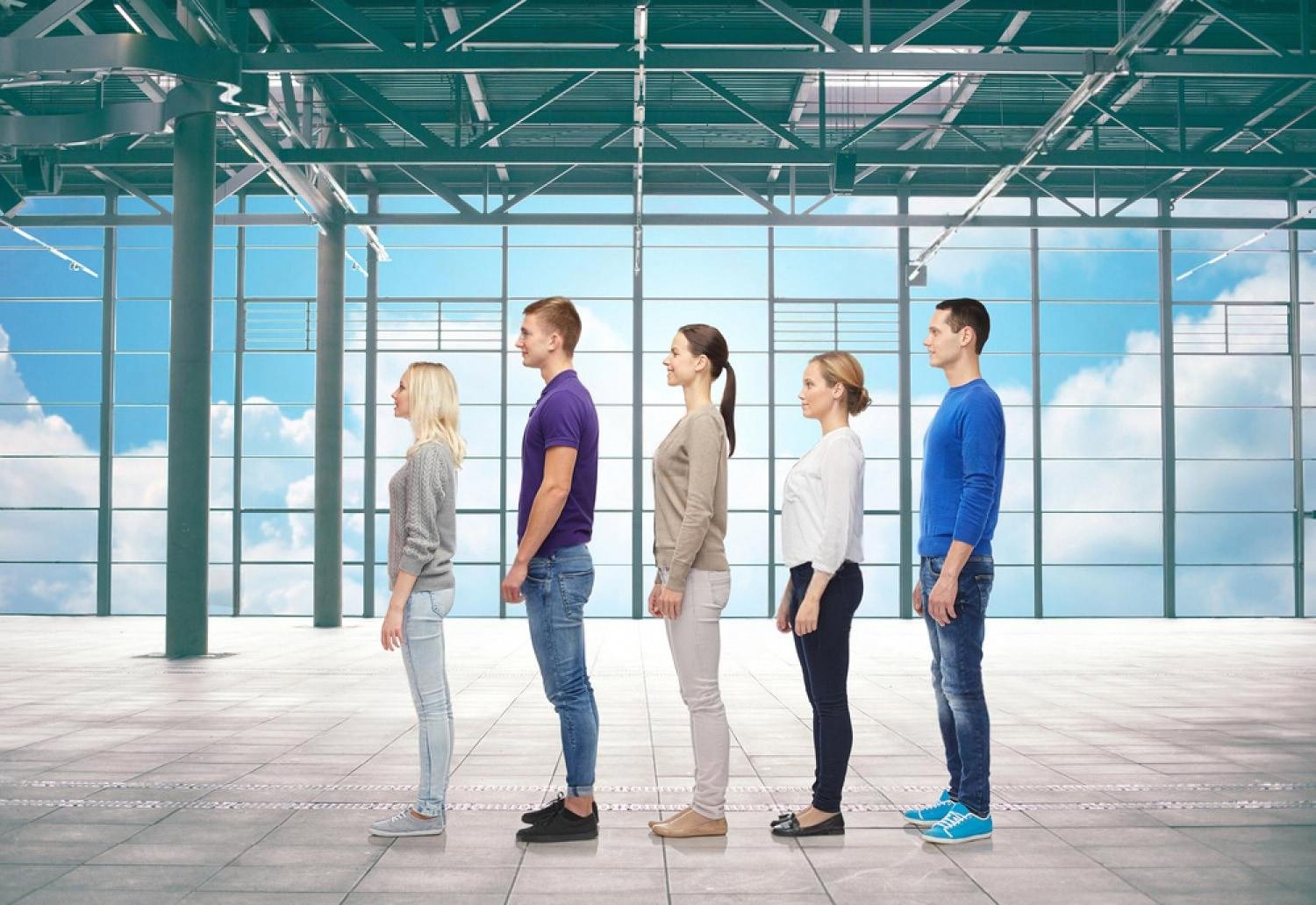 People standing in a single-file line inside a bright modern hall, illustrating the old queue system at UAE visa centers